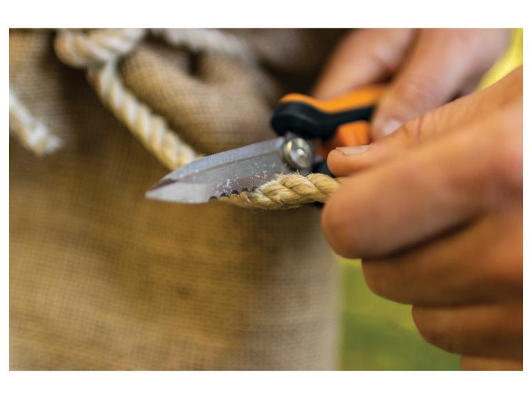 Hände schneiden Seil mit einem Messer, mit Jute-Stoff im Hintergrund.