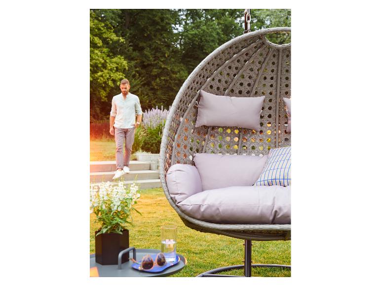 Hängesessel mit Kissen und ein Mann, der eine Treppe im Garten hinuntergeht.