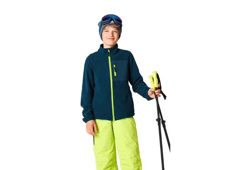 Junge in Skikleidung mit Skistöcken