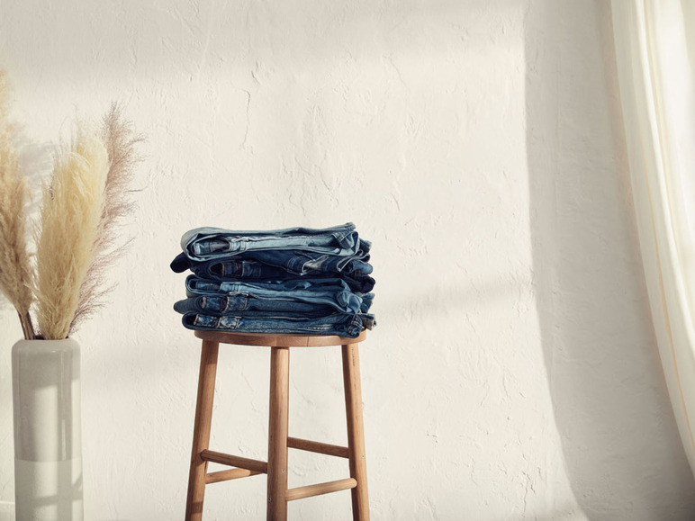 Ein Stapel Jeans auf einem Holzhocker