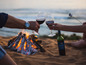 Zwei Gläser Rotwein und eine Flasche 'Botzavino' Wein neben einem Lagerfeuer am Strand.