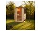 Outdoor-Holzsauna mit Schindeldach in einem grünen Garten.