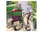 Eine Person benutzt einen rosa Rollator mit Sitz im Park.