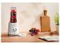 Weißer Personal Blender mit Beeren, einer Obstschale und einem Holzschneidebrett auf einer Küchenarbeitsplatte.