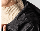 Nahaufnahme einer Frau in einer schwarzen Kapuzenjacke und einem Strickpullover.