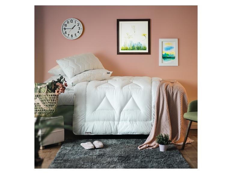 Schlafzimmer mit Bett, weißer Bettdecke, Kissen, Wanduhr und Bildern.