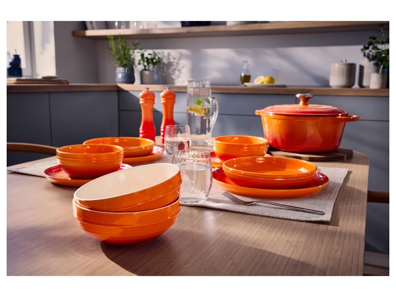 Orangenes Salz- und Pfeffermühlen-Set auf einem gedeckten Tisch.