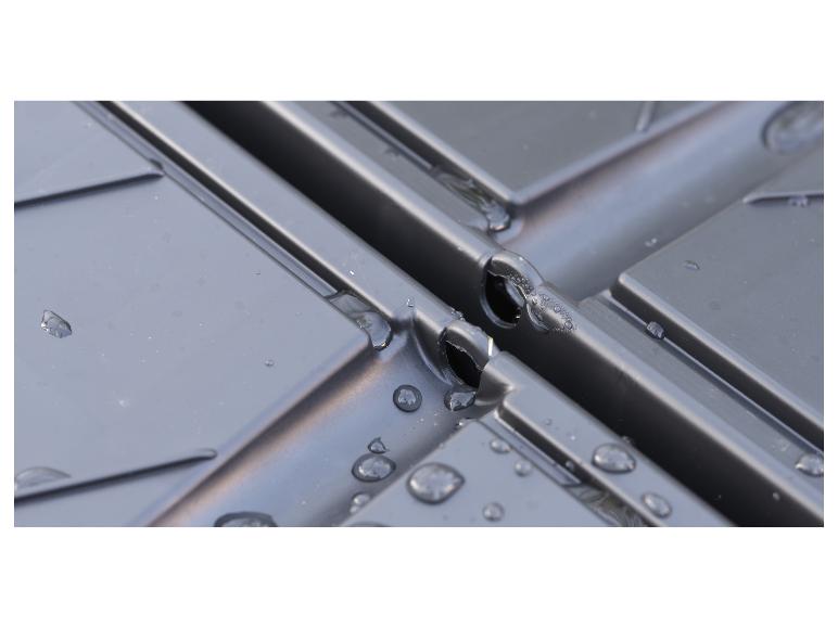 Nahaufnahme von schwarzen modularen Fliesen mit Wassertropfen, wahrscheinlich zur Entwässerung oder Bewässerung.