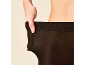 Frau zieht schwarze Strumpfhose an der Taille zurecht.