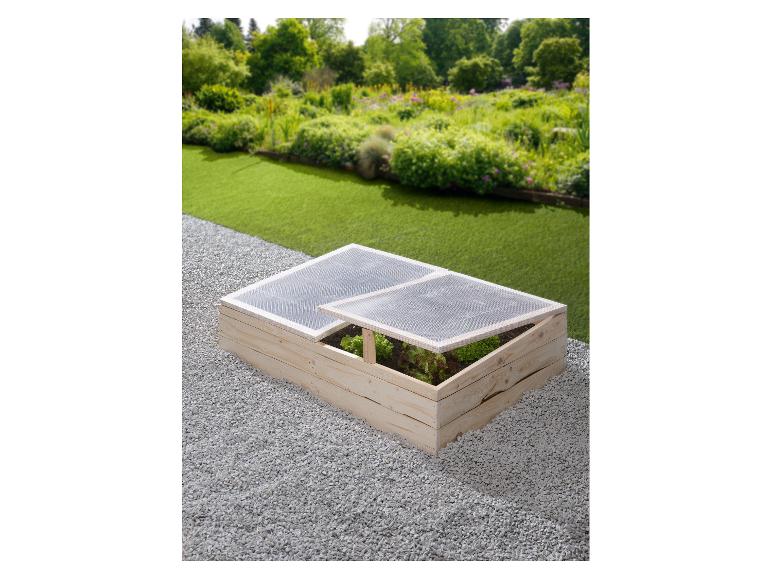 Holz-Frühbeet mit transparentem Deckel und Gemüse im Garten.
