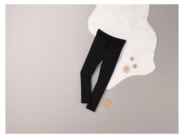 Schwarze Leggings auf grauem Hintergrund mit hölzernen Schneeflocken-Verzierungen.