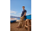 Mann in blauem T-Shirt und beiger Hose am Strand mit Booten, Nummer 7GC305.95