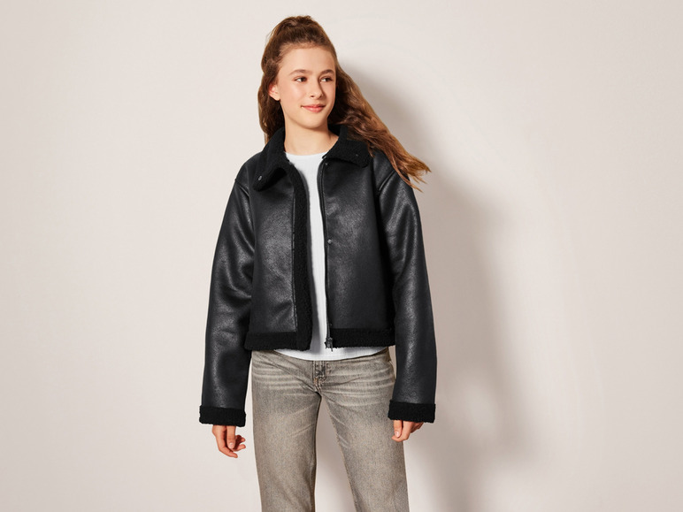 Eine Frau trägt eine schwarze Lederjacke und Jeans.