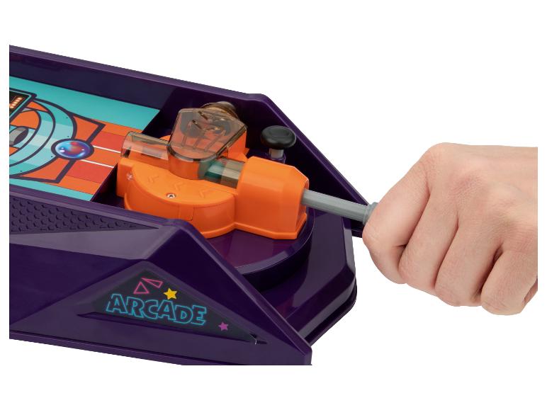 Eine Hand bedient ein violettes Brettspiel mit einem orangefarbenen Hebel