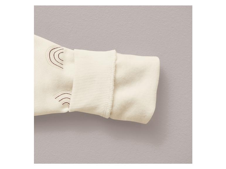 Ein weißer Pullover mit Regenbogenmuster und Rippstrickbündchen.