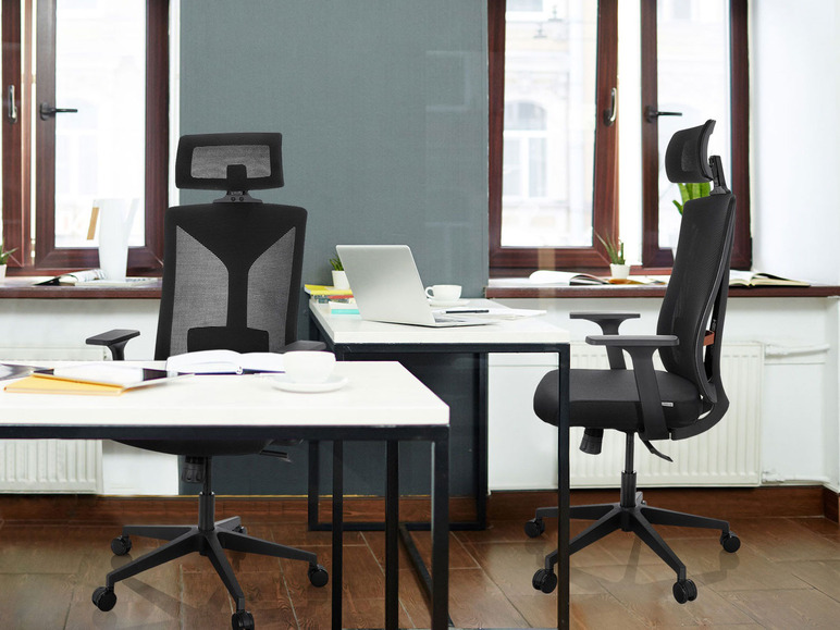 Zwei schwarze Bürostühle mit Kopfstützen in einem Büro.