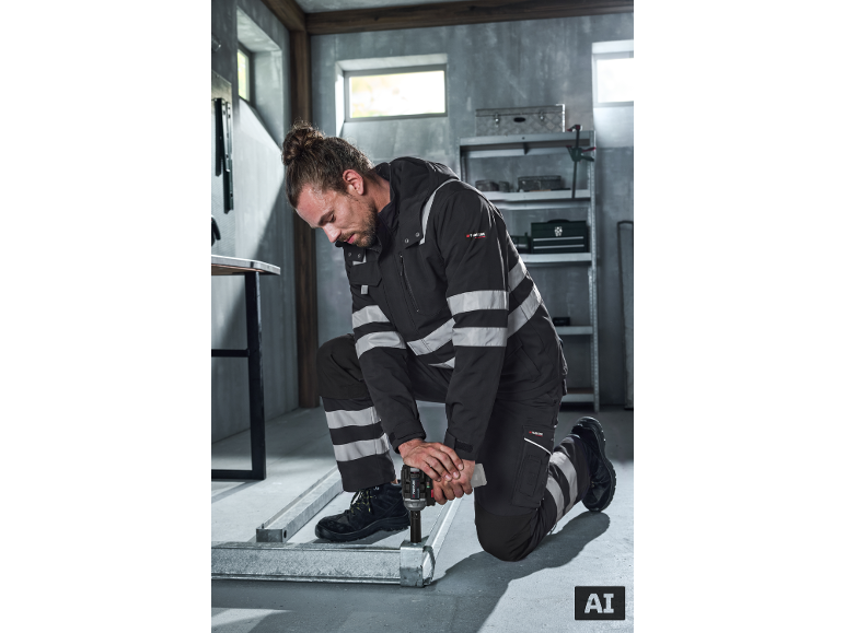 Mann in reflektierender Arbeitskleidung mit Werkzeug arbeitet an Metallkonstruktionen.