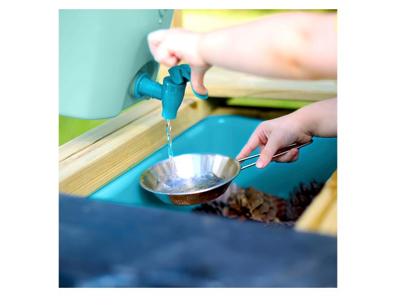 Kind gießt Wasser aus dem Wasserhahn in eine Pfanne im Wasserspieltisch.