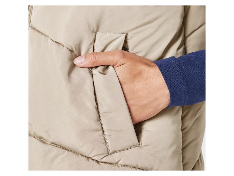 Eine Hand in der Tasche einer beige Winterjacke.