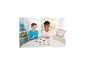 Zwei Kinder spielen mit Bügelperlen und kreieren bunte Formen auf einem weißen Tisch.