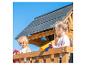 Zwei Kinder spielen auf einem Holzspielhaus mit rotem Lenkrad und gelbem Teleskop.