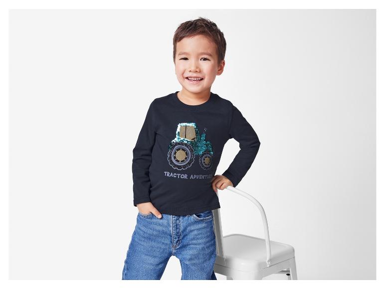 Kleiner Junge mit Traktor-Shirt und Jeans.