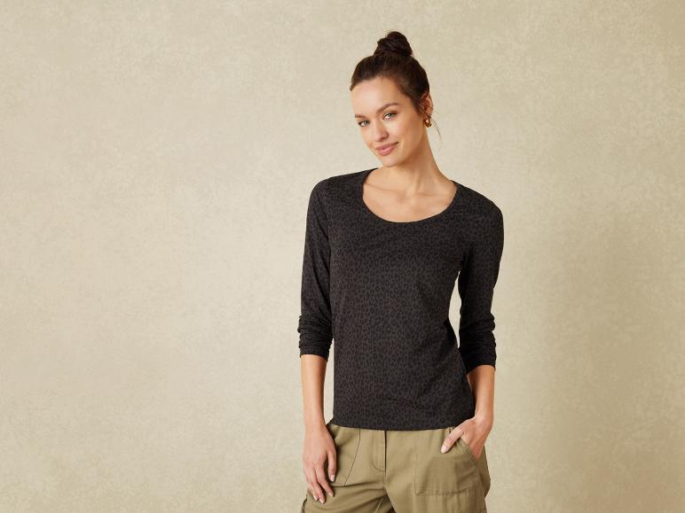 Eine Frau trägt ein schwarzes Langarmshirt mit Leopardenmuster und eine Khakihose.