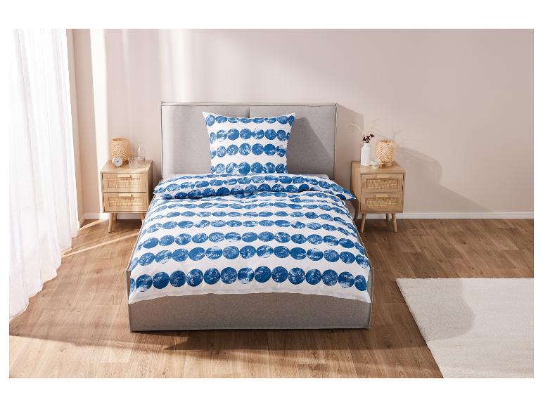 Ein Bett mit einer weißen Bettdecke mit blauen Punkten und passenden Kissen.