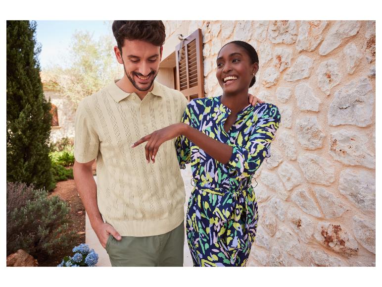 Ein Mann in einem beigefarbenen Poloshirt und eine Frau in einem bunten Kleid lachen zusammen.
