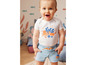 Baby in einem weißen Shirt mit Oktopus und einer blauen Jeans-Shorts.