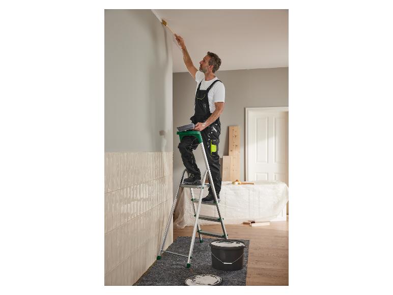 Ein Mann streicht eine Wand mit einer Leiter und einem Pinsel.