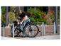 Frau sichert ein E-Citybike mit einem Schloss an einem Fahrradständer.
