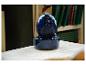 Blauer Keramik-Zimmerbrunnen auf einem Holztisch, mit Büchern im Hintergrund.