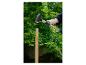 PARKSIDE Vorschlaghammer schlägt auf einen Holzpfahl vor grünen Bäumen.