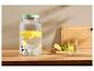 Getränkespender aus Glas mit Zitronen und Minze, Wasserglas mit Zitrone auf Holztisch.