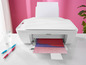 Ein weißer HP DeskJet 2710e Drucker mit einem farbigen Blatt Papier, das aus ihm herausgezogen wird.
