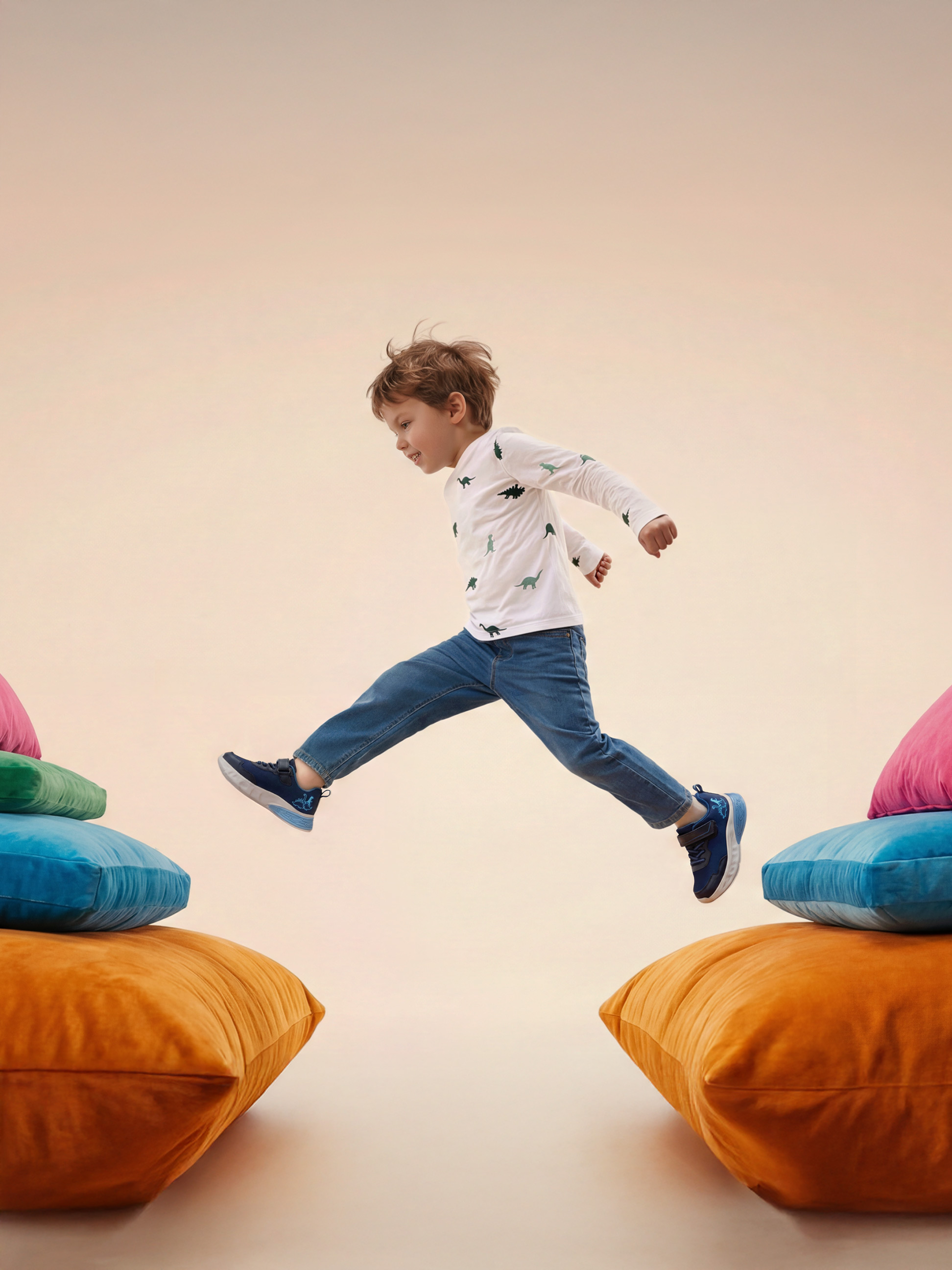 Kind springt zwischen bunten Kissen, trägt ein Dinosaurier-T-Shirt und Jeans.