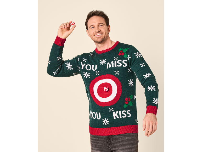 Mann in einem grünen Weihnachtspullover mit einem Zielscheiben-Spiel und dem Text 'YOU MISS YOU KISS'.