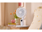 Weißer Tischventilator auf einem hölzernen Nachttisch neben dem Bett.