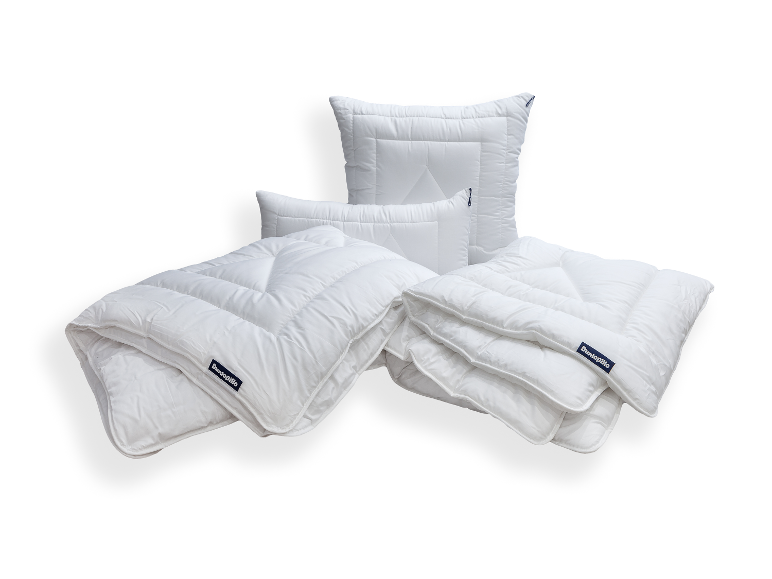 Weiße Bettdecken und Kissen mit Steppmuster, auf weißem Hintergrund arrangiert.