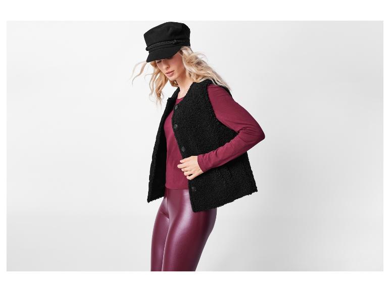 Frau trägt eine schwarze Sherpa-Weste und burgunderfarbene Leggings.