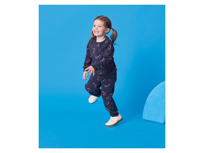 Kleines Mädchen in dunkelblauem Trainingsanzug mit Zuckerstangenmuster.
