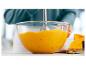 Eine Person püriert Kürbiscremesuppe in einer Glasschüssel mit einem Stabmixer.
