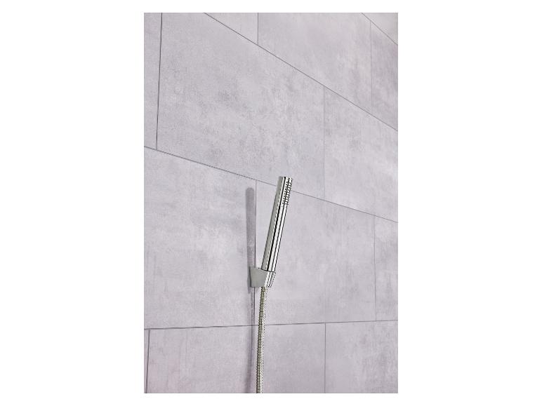 Ein moderner Chrom-Duschkopf und Schlauch an einer hellgrauen Fliesenwand.