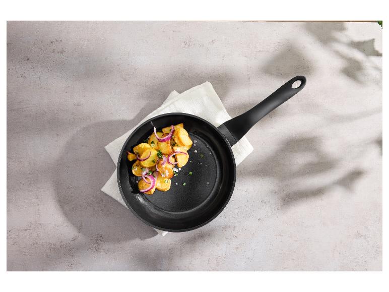 Bratpfanne mit Bratkartoffeln und roten Zwiebeln auf einer weißen Serviette.