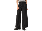 Schwarze weite Hose und graues T-Shirt, getragen mit schwarzen Mokassins.