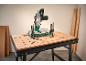 Kappsäge auf einer Werkbank mit Lochplatte, mit Holzplatten und Latten im Hintergrund.