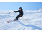 Skifahrer in Skijacke, Skihose, Helm und Skibrille fährt den Berg hinunter.