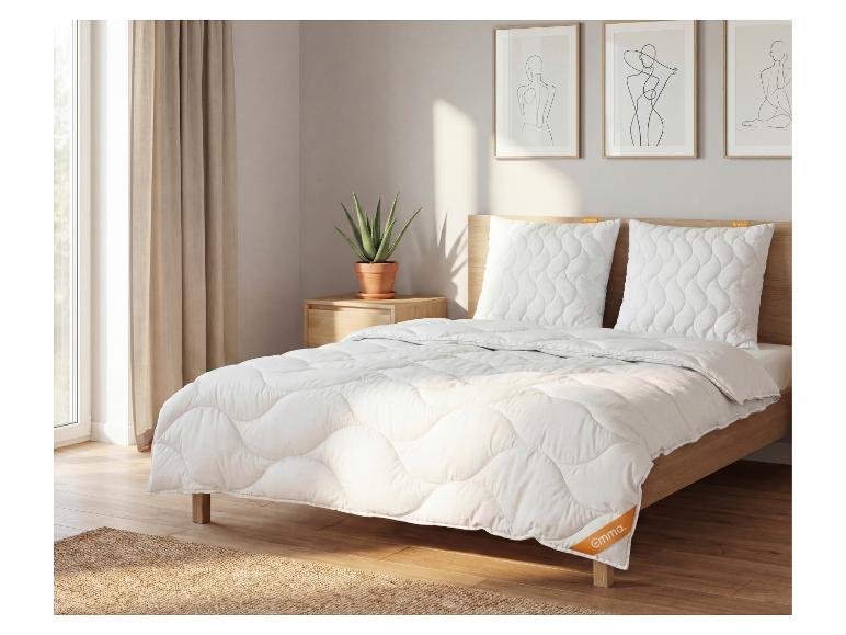 Schlafzimmer mit Bett, weißer gesteppter Bettwäsche, Kissen und Holzrahmen.