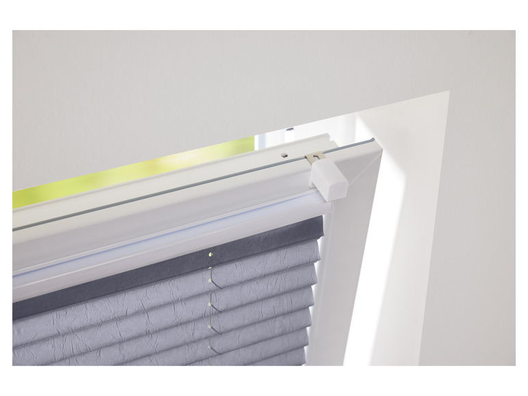 Ein graues Plissee-Rollo an einem weißen Fenster